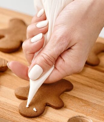 Person Decorating a Gingerbread Man Cookies