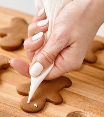 Person Decorating a Gingerbread Man Cookies